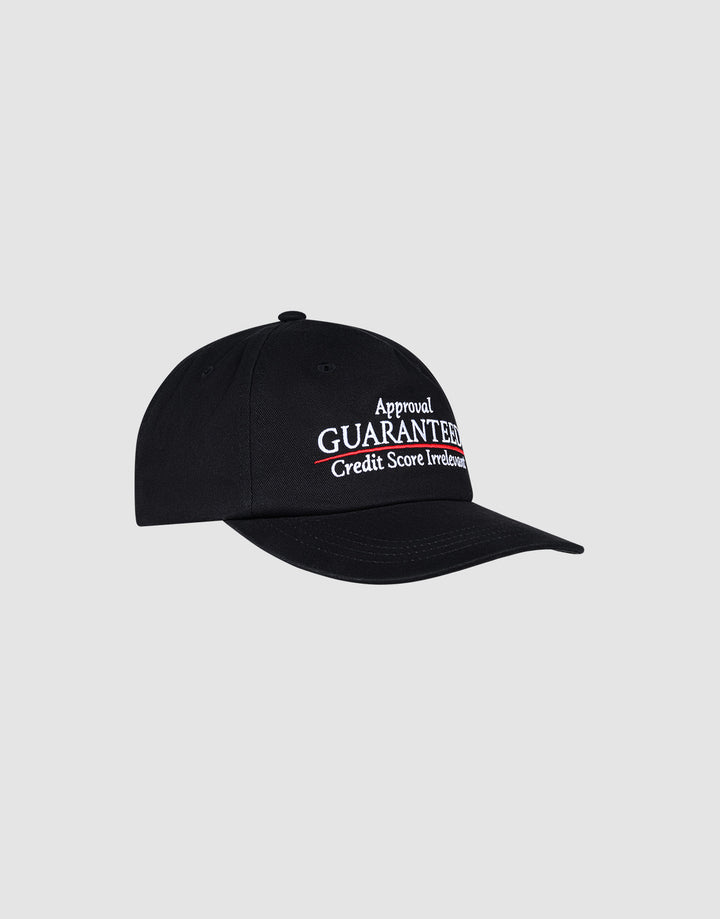 The LFDY Guaranteed Cap by LIVE FAST DIE YOUNG is a black unstructured 5-panel cap made from 100% polyester with a snap closure. It features white and red "Approval GUARANTEED. Credit Score Irrelevant." embroidery on the front, shown on a plain light gray background.