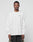 A man faces forward in a LIVE FAST DIE YOUNG Basic Longsleeve, an oversized white cotton shirt with a small green logo print on the chest, paired with black shorts featuring tan side panels, against a plain light gray background.