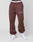 Person wears maroon Wide Cuff Jogger by LIVE FAST DIE YOUNG, featuring the Live Fast logo on the left thigh, a white waistband visible above, and white sneakers, standing against a plain light background.