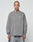 A person with a shaved head and neck tattoo models the LIVE FAST DIE YOUNG Basic Longsleeve—an oversize fit, 100% cotton gray shirt with a subtle chest logo—paired with gray pants against a plain white background.