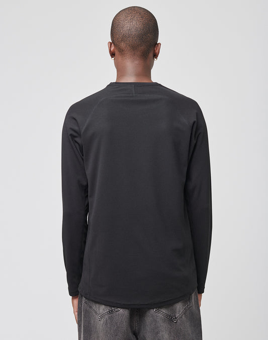 A person with a shaved head is shown from behind, wearing a LIVE FAST DIE YOUNG Live Fast Sports Longsleeve and faded black jeans against a plain light gray background.