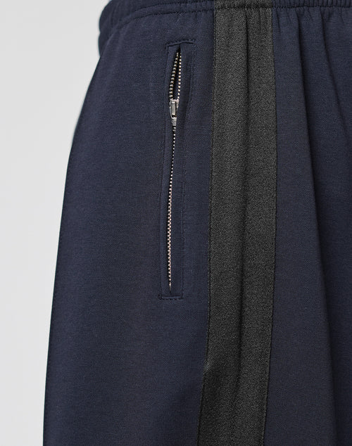 Close-up of the LFDY Striped Jogger by LIVE FAST DIE YOUNG in navy blue, featuring a vertical Fischgräten-Tape stripe, elastic waistband, and a zippered side pocket.