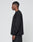 A man in profile faces left, dressed in the LIVE FAST DIE YOUNG Basic Longsleeve—100% Baumwolle black shirt—and oversize-fit black textured pants, against a plain light gray background.