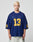 A person with short, bleached blond hair wears the blue LFDY Mesh Jersey by LIVE FAST DIE YOUNG, featuring an oversize fit, yellow number 13 on the front and sleeves, and a V-Ausschnitt, standing against a plain light background.