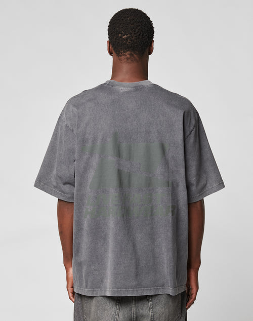 A person wears an oversize fit, faded gray LFDY Hardwear Tee by LIVE FAST DIE YOUNG, featuring a large dark backprint and text, standing with their back to the camera against a plain light background.
