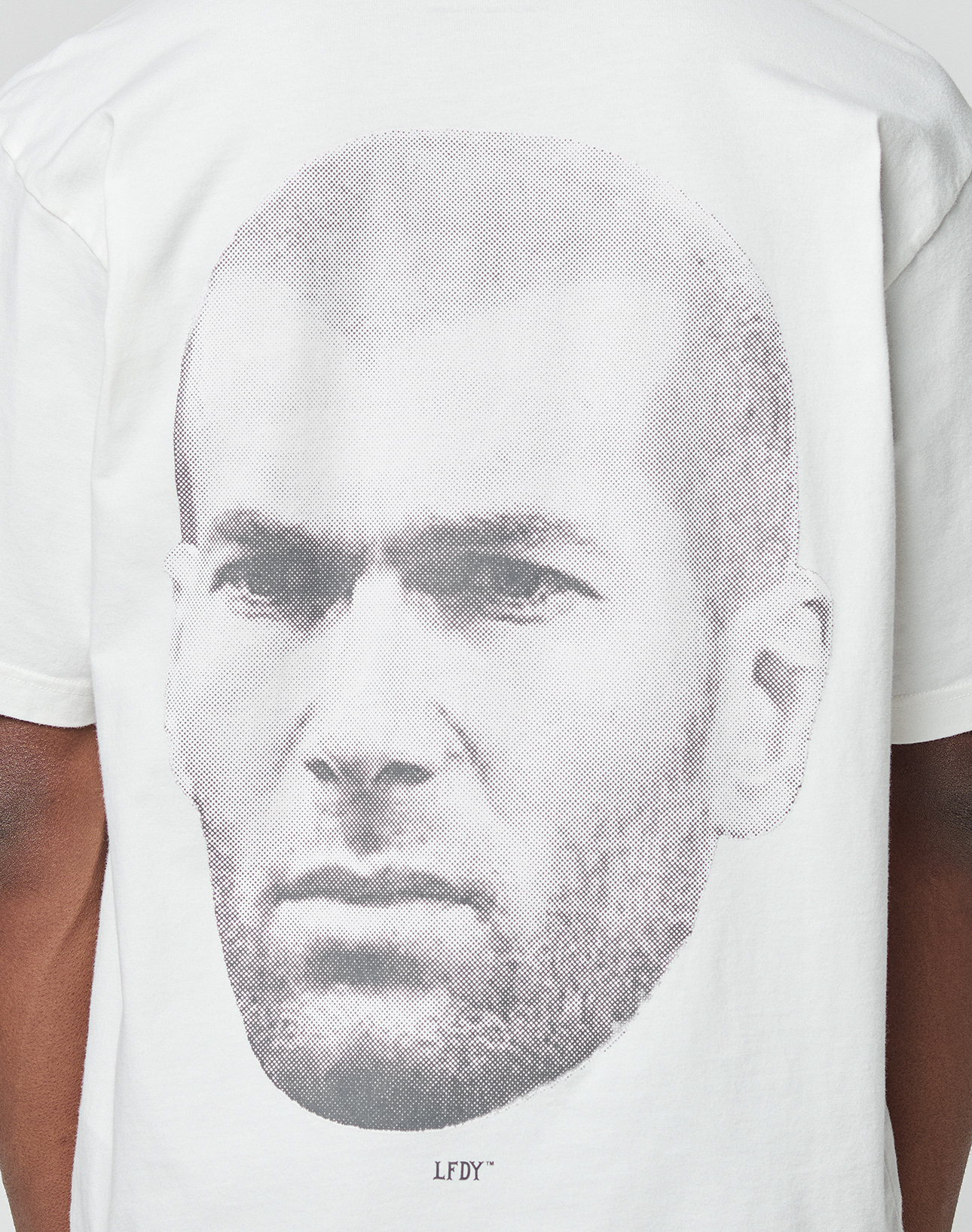 Wearing the LFDY Zizou Tee by LIVE FAST DIE YOUNG: an oversize white 100% Baumwolle shirt with a bold grayscale man's face backprint, small LFDY text beneath, and subtle front and backprint details.
