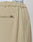 Close-up of beige Wide Casual Pants by LIVE FAST DIE YOUNG, featuring a back pocket, side seam, and a small metallic tag. The waistband of white underwear branded LIVE FAST is visible above the pants.