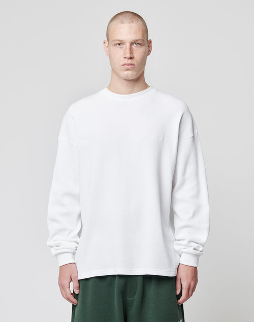 A person with a shaved head wears the LIVE FAST DIE YOUNG Basic Script Waffle Longsleeve in white and dark green pants, standing against a light gray background with a neutral expression.