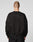 A person with a shaved head is shown from behind, wearing the LIVE FAST DIE YOUNG LFDY Wavy Sweater in black with subtle curved stitching and black pants, standing against a plain light background.