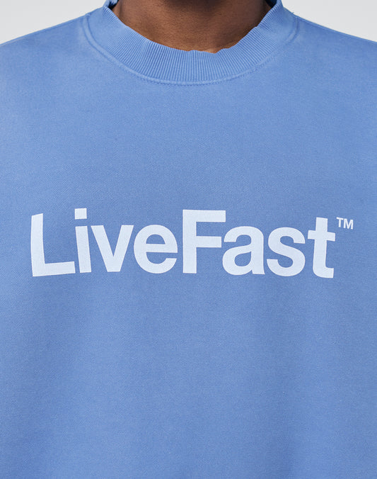 A person wears the Basic LiveFast Sweater by LIVE FAST DIE YOUNG, featuring an Oversize Fit, subtle Faded Look, and bold white LiveFast⢠print across the chest.