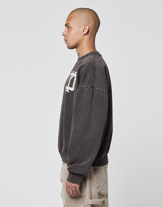 A person with a shaved head and visible tattoos stands in profile against a plain background, wearing the Live Fast DY Sweater by LIVE FAST DIE YOUNG with an applique chest detail and beige pants, exuding a cool vintage vibe.