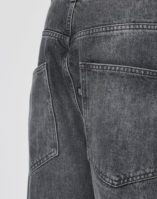 Close-up of the back pocket of LFDY Baggy Denim by LIVE FAST DIE YOUNG, featuring black washed denim, detailed stitching, a small black tag with white text, baggy fit, and made from 100% Baumwolle.