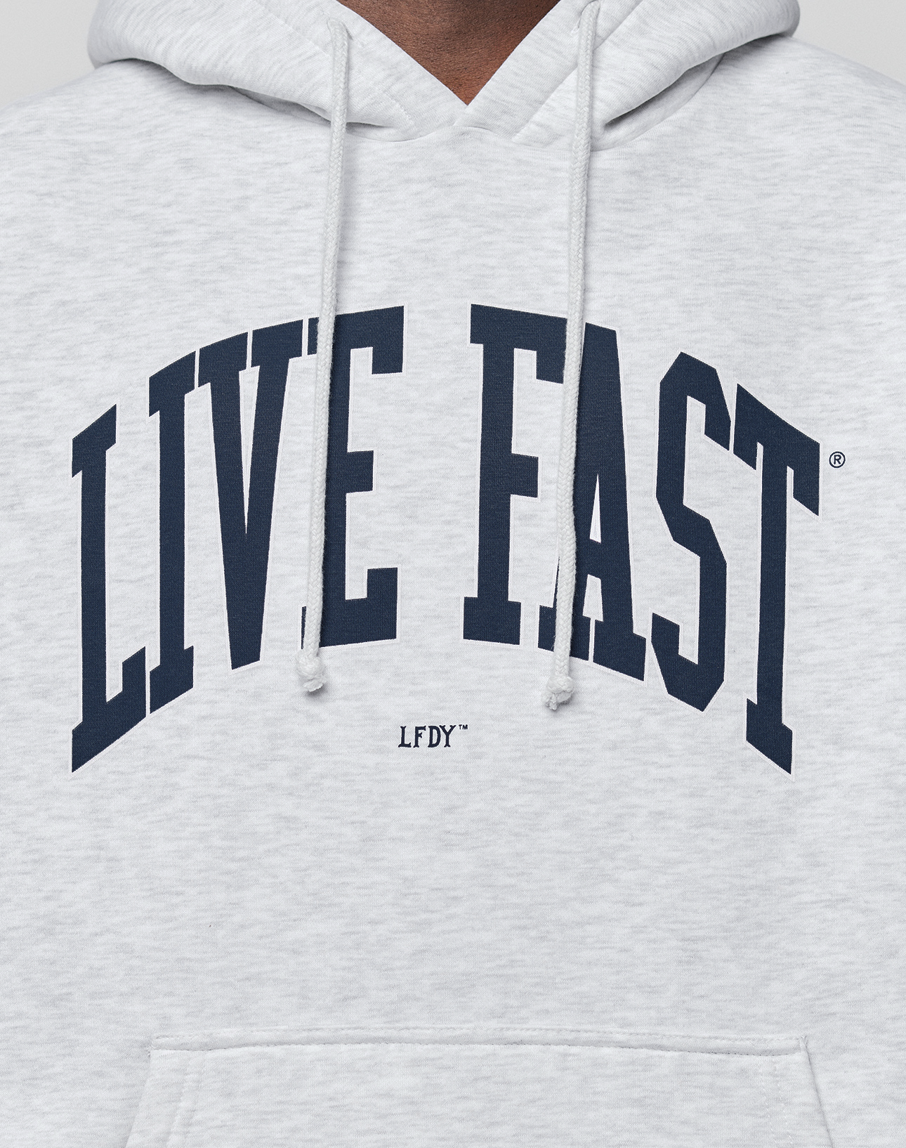 A close-up of the LIVE FAST DIE YOUNG Live Fast College Hooded, an oversized light gray hoodie in soft cotton, with bold navy "LIVE FAST" front print, smaller "LFDY" underneath, and visible drawstrings.