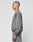A person with a shaved head stands in profile, wearing a faded gray LIVE FAST DIE YOUNG Basic Chest Sweater made from soft Baumwolle, paired with matching sweatpants, against a plain light background.
