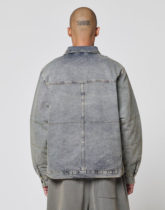 A person with a shaved head and a tattoo on the back is seen from behind, wearing the LIVE FAST DIE YOUNG Puffed Denim Coach Jacket and gray pants, set against a plain light background.
