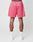 A person is shown from the back wearing LIVE FAST DIE YOUNG LFDY Oval Mesh Shorts in bright pink with a regular fit, elastic waistband, and back pocket, paired with white socks and sneakers. The background is plain white.
