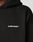 Close-up of the black Live Fast Plain Hooded by LIVE FAST DIE YOUNG, featuring an oversize fit and LIVE FAST™ in white uppercase letters on the chest. Made from a soft cotton-polyester blend; only part of the shoulder, neck, and hood are visible.