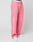 Person wearing LIVE FAST DIE YOUNG Live Fast Boucle Pants—loose-fitting, pink with straight leg and white “LIVE FAST” on the left leg. Features drawstring, elastic waistband with repeated LIVE FAST text, paired with white sneakers.
