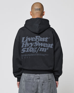 A person with a shaved head and a tattoo on the back of their scalp wears the LIVE FAST DIE YOUNG Basic 510 Hooded Zip in Oversize Fit with a large gray Backprint text, paired with gray jeans.