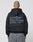 A person with a shaved head and a tattoo on the back of their scalp wears the LIVE FAST DIE YOUNG Basic 510 Hooded Zip in Oversize Fit with a large gray Backprint text, paired with gray jeans.