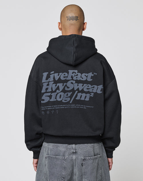 A person with a shaved head and a tattoo on the back of their scalp wears the LIVE FAST DIE YOUNG Basic 510 Hooded Zip in Oversize Fit with a large gray Backprint text, paired with gray jeans.