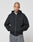 A person with a shaved head wears the LIVE FAST DIE YOUNG Basic 510 Hooded Zip with front and back print and oversize fit, paired with baggy gray jeans, standing hands-in-pockets against a plain light gray background.