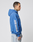 A tattooed person in profile wears the LIVE FAST DIE YOUNG LFDY Team Hooded Zip—an oversize blue hoodie with EUROPE RUN and multilogo Stickereien on the sleeve—paired with light blue jeans, set against a plain white background.