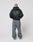 A person with a shaved head, facing away, wears an oversize fit black LIVE FAST DIE YOUNG Basic 510 Hooded Zip hoodie and loose gray vintage-wash jeans, standing against a plain white background.