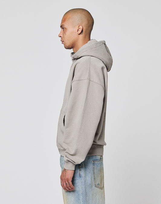 A person with a shaved head stands in profile against a plain background, wearing the LIVE FAST DIE YOUNG Basic 510 Hooded Zip hoodie in light gray and faded blue jeans in vintage wash.