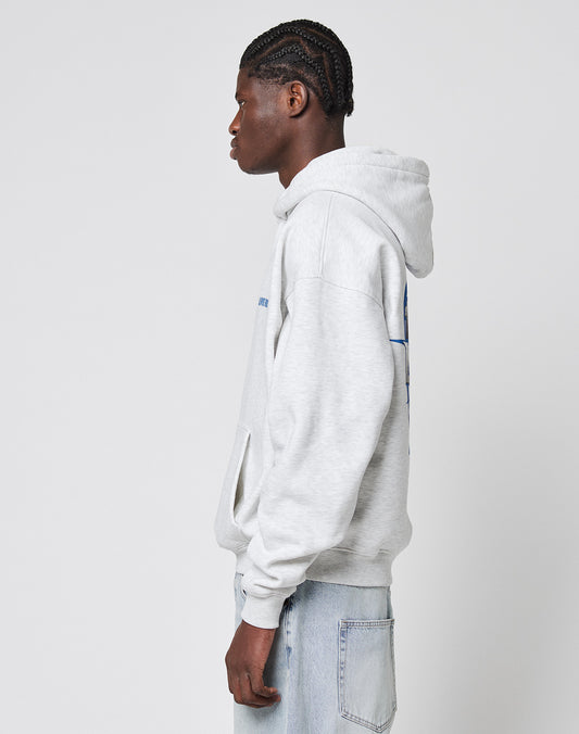 A young man with braided hair stands in profile, wearing an oversize fit light gray LFDY Globe Hooded sweatshirt by LIVE FAST DIE YOUNG, made from a Baumwollemix with Polyester, paired with light blue jeans against a white background.