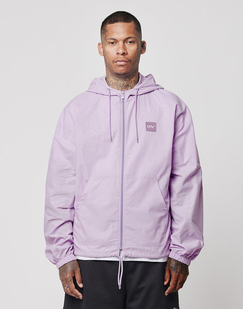 A person with short hair and visible neck tattoos wears a light purple LIVE FAST DIE YOUNG Basic Light Hooded Zip in Regular Fit cotton, standing against a plain light background.