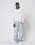 A man in a LIVE FAST DIE YOUNG LFDY Globe Hooded oversize light gray Baumwolle hoodie, loose light blue jeans, and white sneakers stands against a plain white background, gazing to the side with one hand in his pocket.