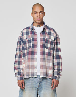 A person stands facing forward against a plain light gray background, wearing the LIVE FAST DIE YOUNG Vintage Flannel—a blue, white, and red plaid shirt with Vintage Waschung and Zweiteiliger Hemdkragen—over a white t-shirt and light blue jeans.