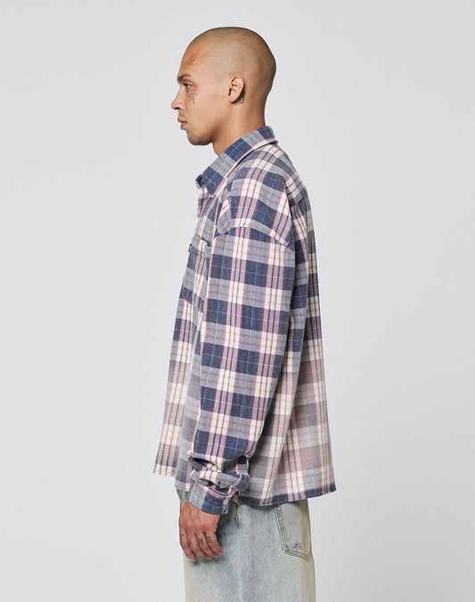 A person with a shaved head wears the LIVE FAST DIE YOUNG Vintage Flannel in blue, white, and pink plaid and light-wash Oversize Fit jeans, posing in profile against a plain white background.