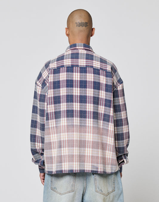 A person with a shaved head and tattoo is seen from behind wearing the LIVE FAST DIE YOUNG Vintage Flannel, an oversized blue, white, and pink plaid shirt with zweiteiliger Hemdkragen, paired with light blue jeans.