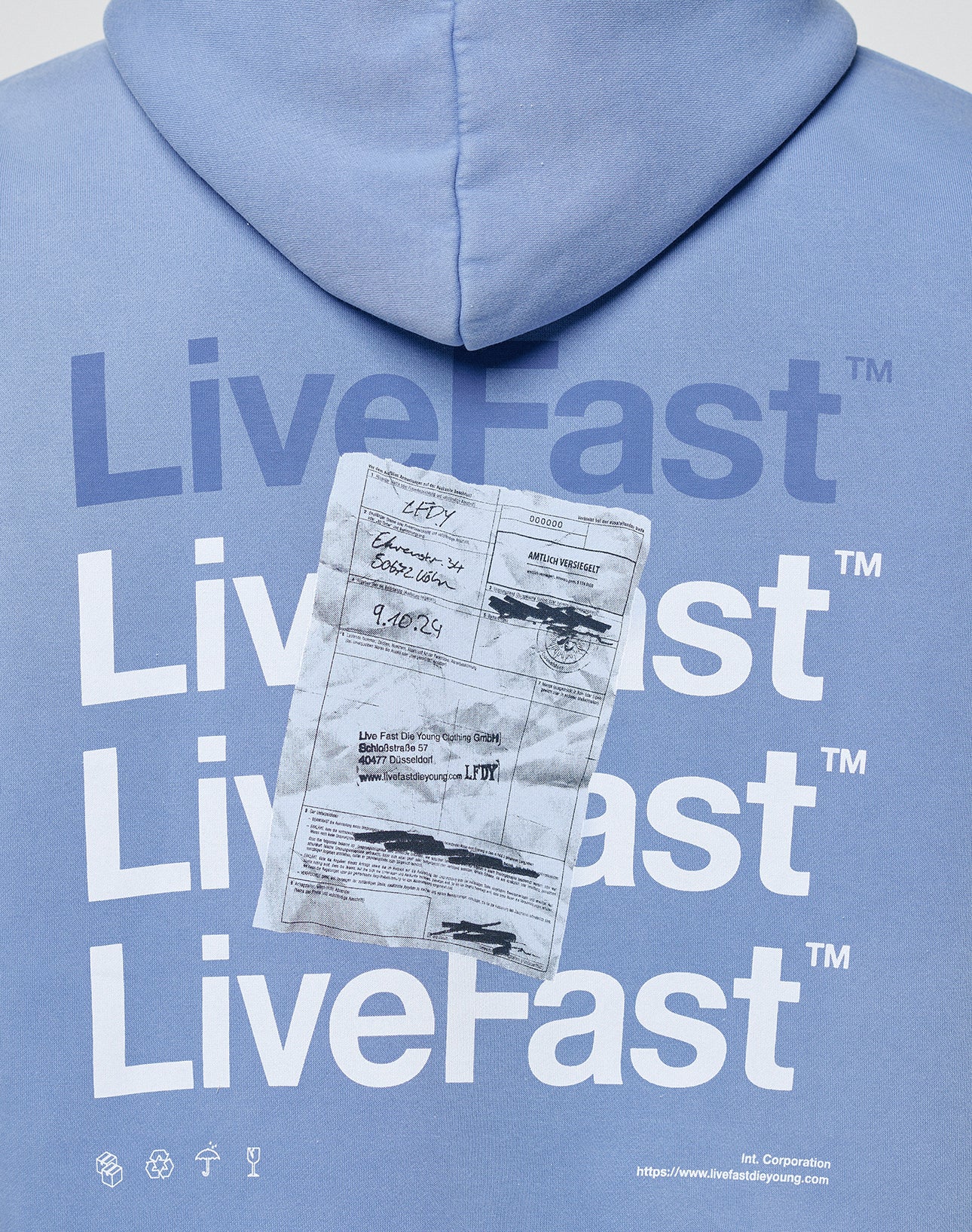 The LIVE FAST DIE YOUNG Basic Evidence Hooded is a blue oversized hoodie with repeated white LiveFast™ text and a faded parking ticket print with handwritten notes and signature on the back for a unique fade effect.