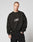 A person with short hair wears the LIVE FAST DIE YOUNG Fuck Die Young Sweater—an oversize black polyester sweatshirt with LIVE FAST VULGAR DIE YOUNG in white—paired with black pants, standing against a plain, light background.