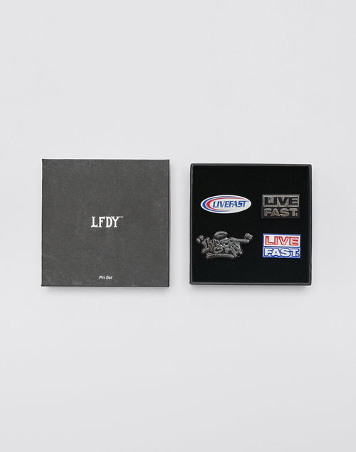 The LFDY Pin Set by LIVE FAST DIE YOUNG features a black LFDY box on the left and an open pin set on the right with four Metall-Pins: two say LIVE FAST, one has LIVEFAST in an oval, and one shows a hand holding a bolt. Steckverschluss LF2403-15348 included.