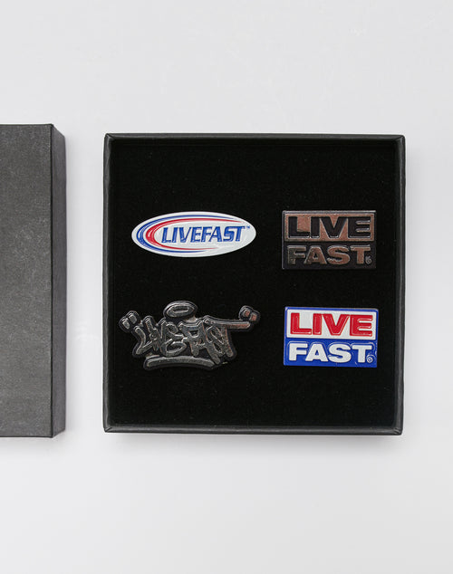 The LFDY Pin Set by LIVE FAST DIE YOUNG includes four Metall-Pins in black packaging: an oval blue-red LIVEFAST pin, a black LIVE FAST pin, a graffiti-style pin, and a LF2403-15348 rectangular red-white-blue pin. All have Steckverschluss fasteners.