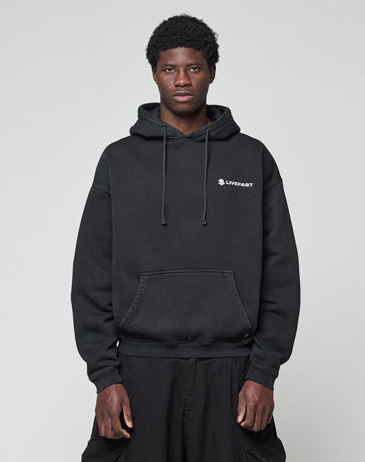 A person stands facing forward wearing a black LFDY Dealership Hooded from LIVE FAST DIE YOUNG with white "LIVEFAST" text on the left chest, matching black pants, and a plain light gray background.
