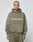 A person with a shaved head models the Basic +49 Hooded by LIVE FAST DIE YOUNG in olive green with white +49LiveFast text, matching sweatpants, and a relaxed oversize fit and faded look against a plain light gray background.