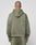 A person with a shaved head models the LIVE FAST DIE YOUNG Basic +49 Hooded sweatshirt and matching pants in olive green, featuring an oversize fit and subtle faded look, standing with their back to the camera against a light gray background.