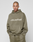 A person faces forward in an olive green Basic +49 Hooded and matching Oversize Fit sweatpants from LIVE FAST DIE YOUNG. The hoodie features a large front pocket and “‘+49LiveFast™’” in white on the chest against a plain, light background.