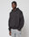 A man in the LIVE FAST DIE YOUNG LFDY Monaco Boys Hooded, featuring an oversize fit and front and back print, pairs it with light blue jeans as he stands against a plain light background, looking at the camera with a neutral expression.
