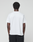 A person with short curly hair faces away from the camera, wearing the LIVE FAST DIE YOUNG Basic Live Fast Graffiti Tee and black pants against a light gray background.