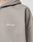 A close-up shows part of a shoulder and hood wearing the taupe Basic Script Hooded Zip by LIVE FAST DIE YOUNG, featuring Vintage-Waschung and a white cursive Live Fast logo embroidered on the chest.