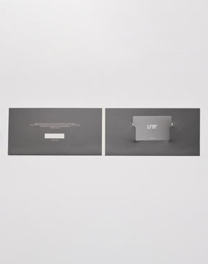 A flat, open black card holder from LIVE FAST DIE YOUNG displays the Gutschein | Gift Card with silver labeling. Text is printed left, the card fits right, all shown as an elegante Geschenkverpackung on a light gray background.