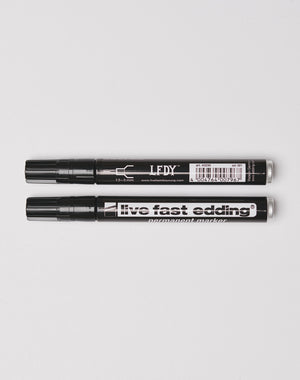 Two black permanent markers with caps rest side by side on a white surface—one labeled LEDY, the other Live Fast Edding by LIVE FAST DIE YOUNG; both are wasserfest and perfect for making lasting marks.