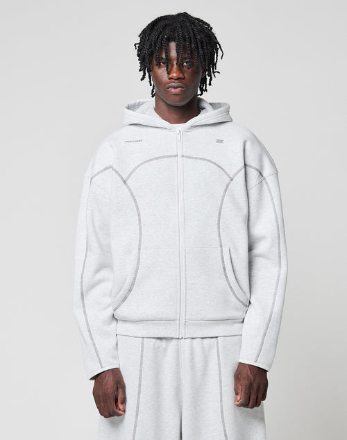 A person with short dreadlocks wears the LFDY Active Fleece Hooded Zip in Oversize Fit by LIVE FAST DIE YOUNG with matching sweatpants, standing against a plain light background and looking directly at the camera.