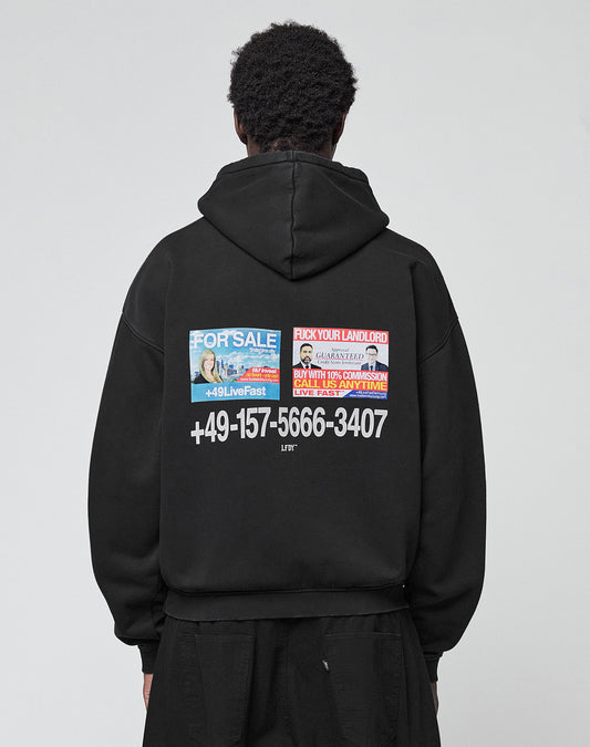 A person is seen from behind wearing the LIVE FAST DIE YOUNG Live Fast Call Us Hooded, an oversize black hoodie made of cotton with bold white text, a phone number, and colorful "For Sale" graphics on front and back, against a plain light background.